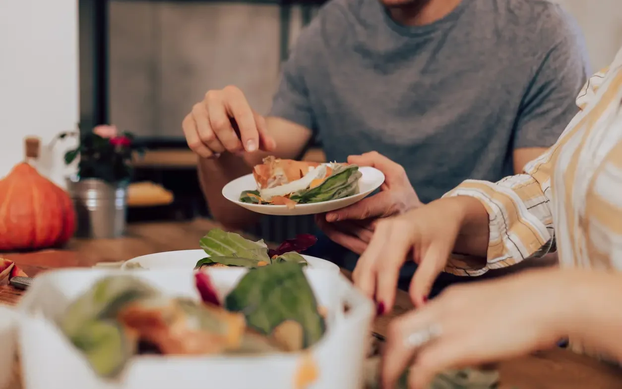 Unrecognizable couple separating fruit and vegetable leftovers for composting.