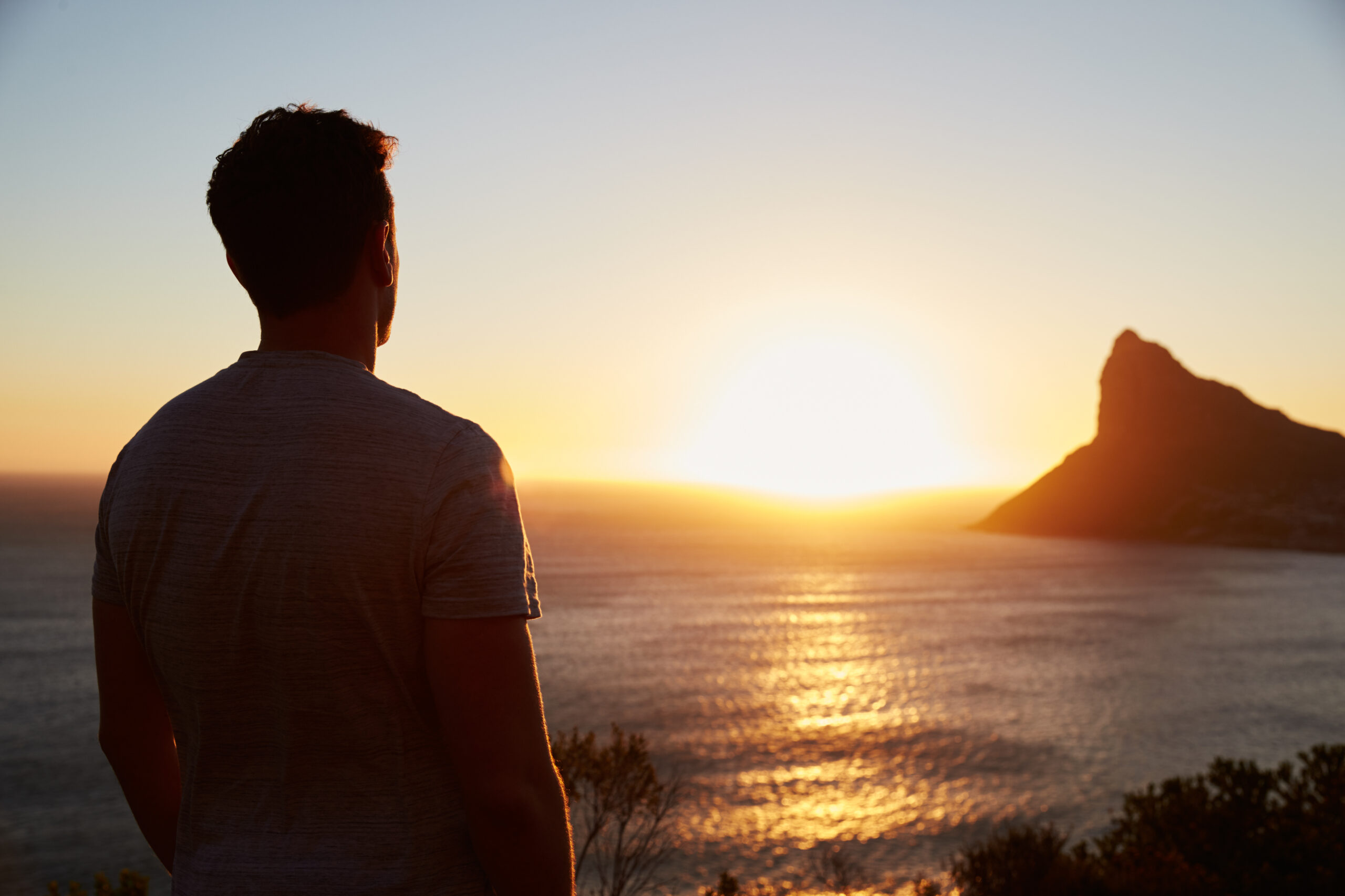 Silhouette,Of,Man,Watching,Sun,Set,Over,Sea,And,Cliffs